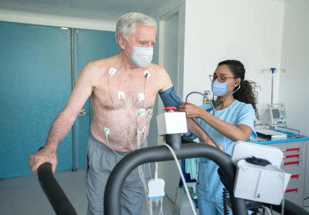 Nurse monitoring a senior patient doing a stress test while wearing facemasks Latin American nurse monitoring a senior patient doing a stress test while wearing facemasks during the COVID-19 pandemic stress test stock pictures, royalty-free photos & images