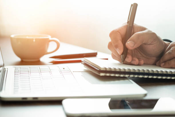 istock man hand using writing pen memo on notebook paper or letter, diary on table desk office. Workplace for student, writer with copy space. business working and learning education concept. 1305085683