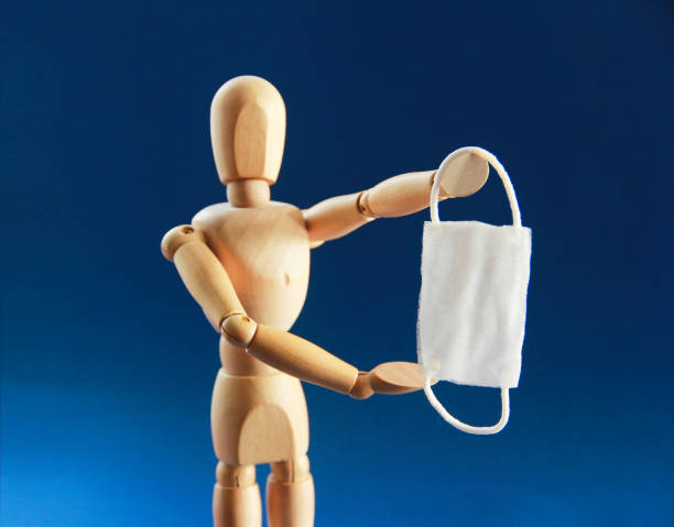 istock a wooden dummy holds a medical mask in its hands 1305086682