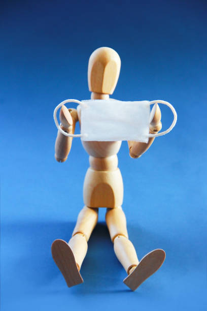 istock a wooden dummy holds a medical mask in its hands 1305086688
