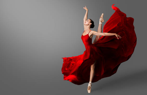 발레리나 댄스. 빨간 드레스를 입은 발레 댄서가 침을 뛰어넘습니다. 발레리나 신발의 여성이 바람에 날아다니는 이브닝 실크 가운에서 춤을 추다 - ballet shoe dancing ballet dancer 뉴스 사진 이미지