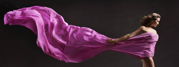Woman dancing. Modern Ballet Dancer with long Fabric Banner flying on Wind in Air. Copy Space. Black Background