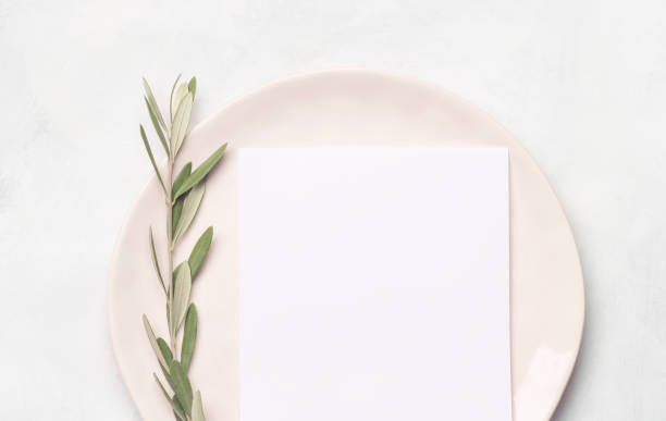 istock Blank of spring greeting card or mock up for invitation on a plate with olive branch with bright sunlight. Flat lay, top view, minimalism 1305087828