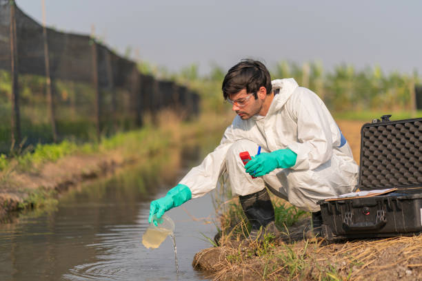 техник в полном теле защитный костюм мера ph образца воды - groundwater стоковые фото и изображения