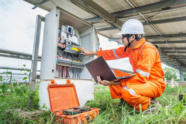Engineers upload data of power energy to a laptop for checking the performance of the solar panel to confirming systems working normally. Concepts professional engineer for the Solar cell power plant. los ingenieros cargan datos de energía eléctrica en un ordenador portátil para comprobar el rendimiento del panel solar para confirmar el funcionamiento de los sistemas con normalidad. ingeniero profesional de conceptos para la planta de energía de cé