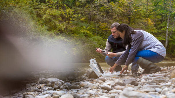 istock Man and woman squatting at case with testing equipment. Preparing for water quality test in river. 1305091871