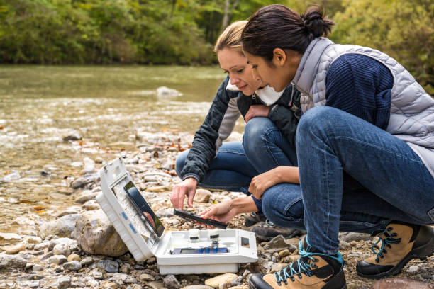 istock Two female biological researchers discussing measured data. Analyzing water quality in mountain river. 1305091942