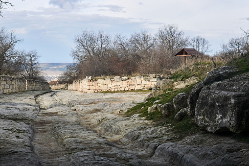 ancient road with ruts from carts in stone among the ruins of the medieval city of Chufut-Kale, Crimea