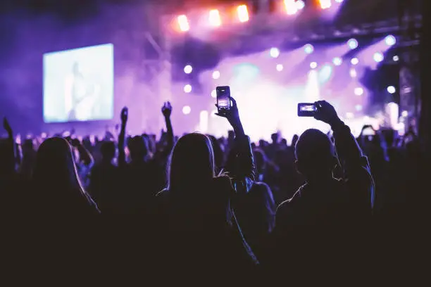 Photo of People holding their smart phones and photographing concert.