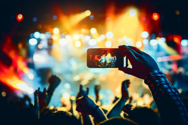 男はスマートフォンを使ってコンサートホールでショーの写真を撮ります。 - popular music concert mobile phone smart phone telephone ストックフォトと画像