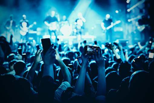 A lot of hands with the smartphone turned on to record or take pictures during the live concert