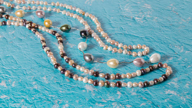 istock Different long natural  multicolored  pearl beads are nicely laid out on a blue textured surface. 1305094968