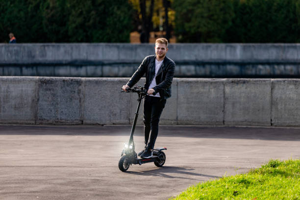 istock Handsome bearded guy with technological eco-friendly electric kick scooter. Concept with copy space at the street in a park near river 1305095075