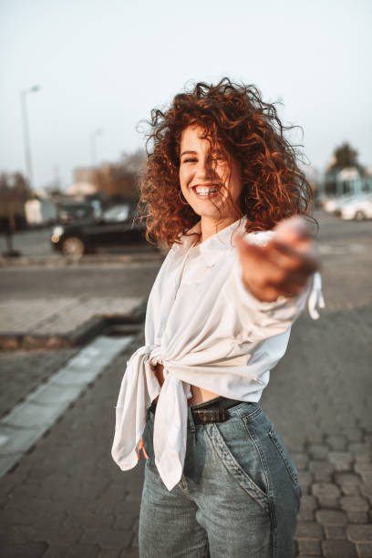 istock Cute Curly Female Offering Her Hand For A Walk On Parking Lot 1305095366