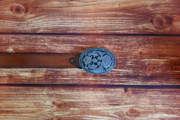 Leather cowboy belt with oval patterned buckle on the wooden background
