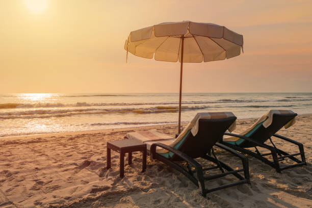 istock Sun umbrellas and chairs on tropical beach with sunset 1305096465