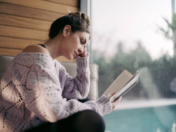 istock Young Woman Reading Book At Home 1305096946