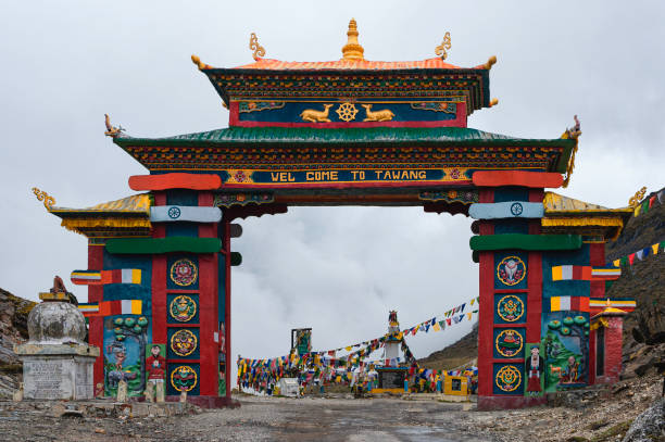 Colorful gateway with Buddhist prayer flags in Himalayas. Tawang, India. Colorful gateway with Buddhist prayer flags fluttering in breeze flanked by Himalayas with fog flowing in at mountain pass near Tawang, Arunachal Pradesh, India. guwahati stock pictures, royalty-free photos & images