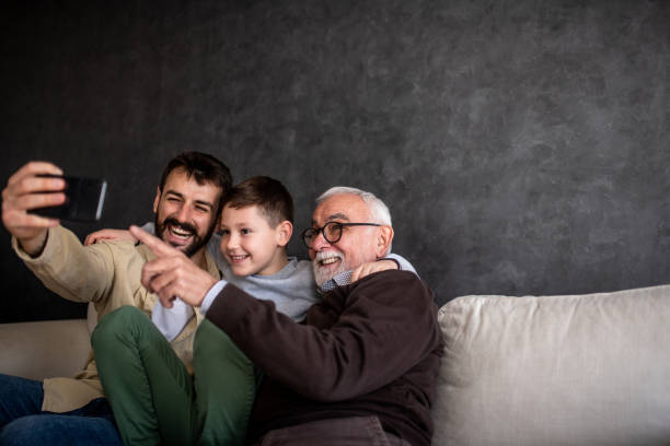 il giovane si sta facendo un selfie con il figlio e il nonno. - grandparent family multi generation family technology foto e immagini stock