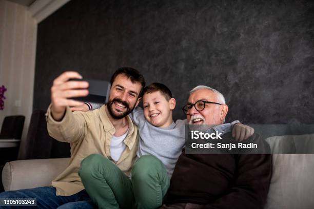 Smiling Boys Are Sitting On Sofa Bed And Taking Selfie Stock Photo - Download Image Now