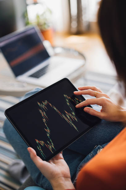 istock Women in Business: An Anonumous Businesswoman Using a Digital Tablet for Online Trading while Working from Home 1305103350