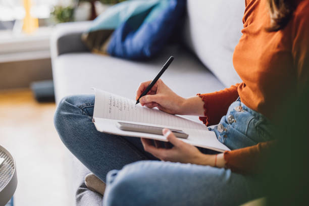 istock Women in Business: Anonymous Young Businesswoman Taking Notes While Working from Home 1305103358