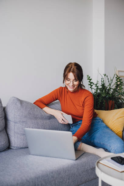 istock Student Life: A Beautiful Young Woman Using a Laptop While Relaxing at Home 1305103418