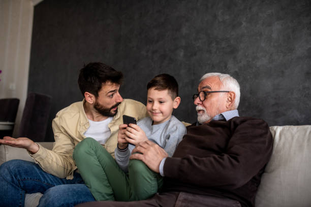 istock Young boy is sitting on the sofa bed by his father and gradfather. 1305103577