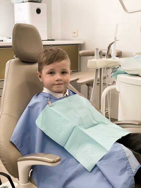 Child in the dental chair treats teeth The child is sitting in a dental chair, he came to check his baby teeth. The baby was not found to have caries, so he smiles very happily at the camera. dental drill stock pictures, royalty-free photos & images