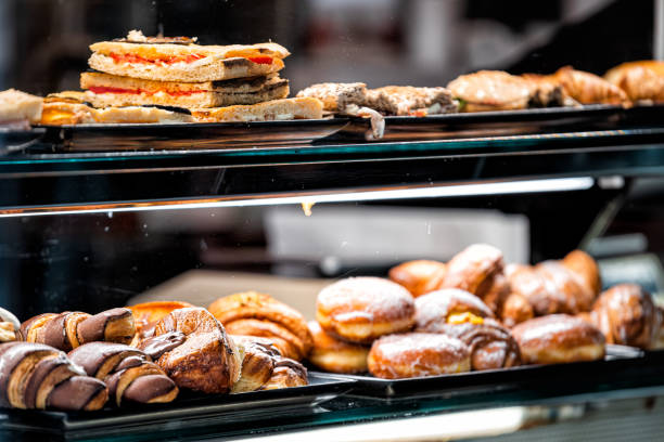 istock Many different various assortment of chocolate sugar donuts baked goods closeup on bakery display behind glass window in Siena, Italy 1305106784