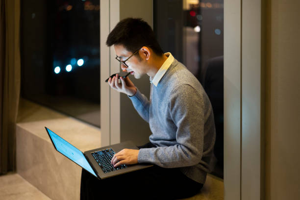 istock Asian man making a call while working at home with laptop at night by the window 1305107255