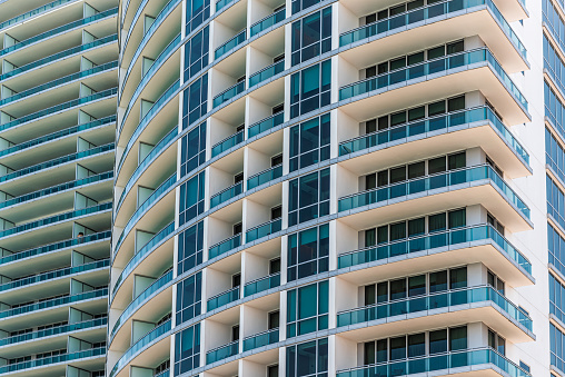Abstract view on residential apartment condo condominium complex building with windows balconies painted in white blue on sunny day