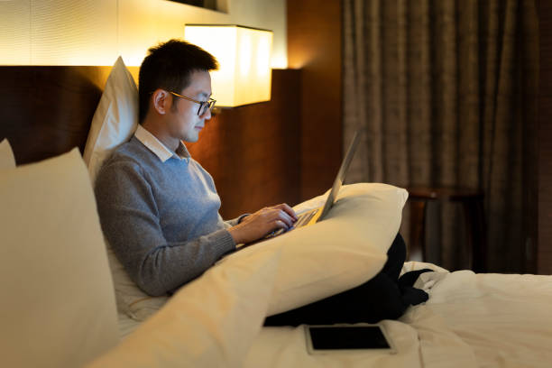 istock Asian man working on bed with laptop at night 1305109832