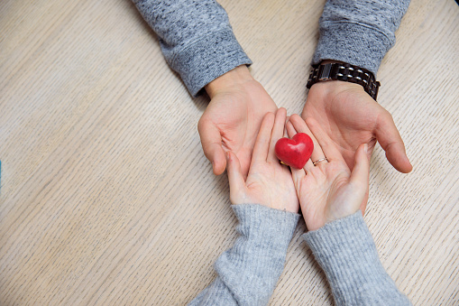 woman and man hand holding red heart