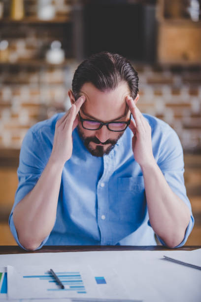istock tired businessman with migraine after work 1305123455