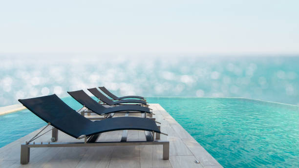 istock Luxury poolside with sun beds and deck chairs over blue sea. Tranquil luxury vacation background. Recreational and relaxing beach scene 1305124814