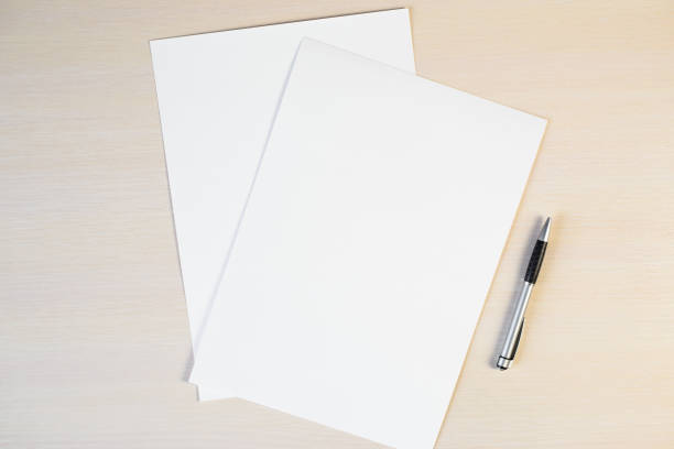 istock Blank sheets of white paper and pen on the table, mock up. Copy space, flat lay 1305125049