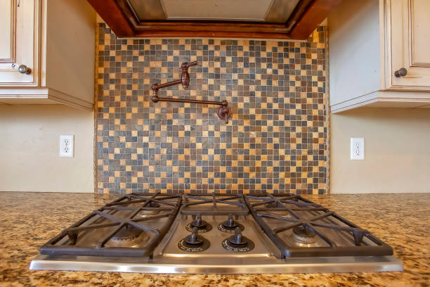 istock Cooktop and exhaust hood inside kitchen with faucet on the tile backsplash wall 1305126189