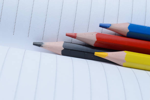 istock four multi-colored pencils - blue, red, yellow, black. lie on an open notebook. 1305126273