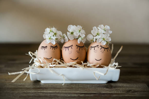 istock Brown hand drawn eggs with faces in the nest, with blooming flowers. Easter, Holiday concept, gift card for your design, place for text. Minimalist. 1305126342