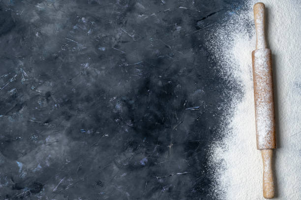 istock Rolling pin and white flour on a dark surface with free space for text . Top view. 1305127052