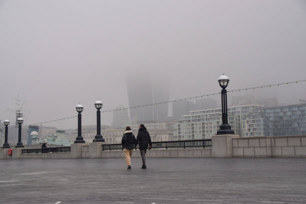 City of London obscured by fog London, United Kingdom - March 3 2021: People walk past a barely visible City of London skyline during the third national coronavirus lockdown, as dense fog engulfed the capital. waterloo bridge stock pictures, royalty-free photos & images