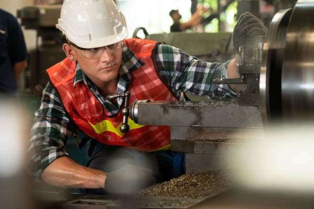 le travailleur ou l’ingénieur intelligent d’usine font le travail de machine dans un atelier de fabrication - ouvrier à la chaîne photos et images de collection