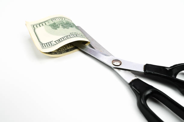 istock Scissors cut the dollar, on an isolated white background 1305128365