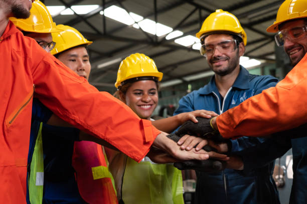 geschickte arbeiter stehen zusammen und zeigen teamarbeit in der fabrik. - warehouse worker stock-fotos und bilder