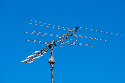 Outdoor TV antenna mounted on pole. Beautiful blue sky background