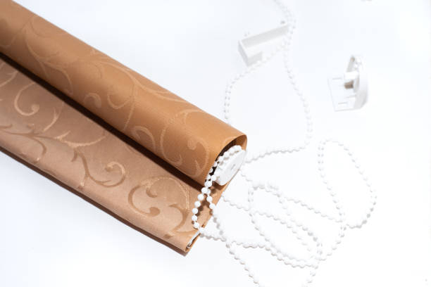 istock Beige textile roller blinds with manual adjustment mechanism on a white background. Home improvement 1305134847