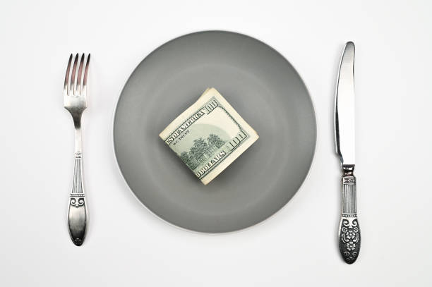 istock Hundred dollar bill on plate, with fork and knife on isolated white background 1305137114