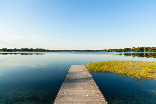 A woman relaxing by a small and quiet fishing lake in the Laurentides (Laurentians), Quebec, during a sunrise of summer.