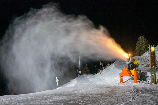 Snow blower at night making snow. Snow cannon